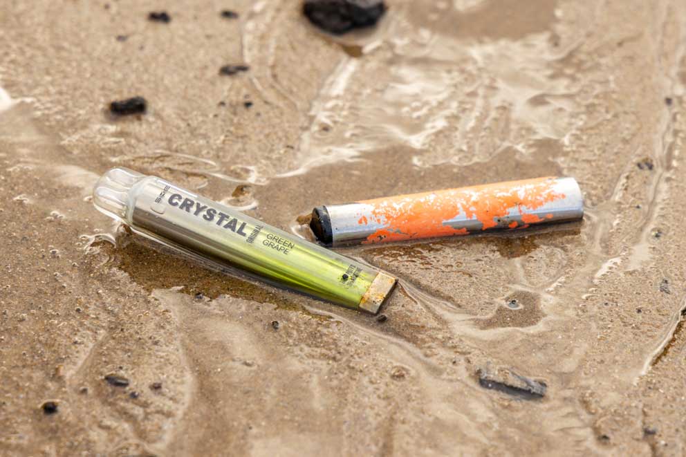 Two discarded vapes in the sand.