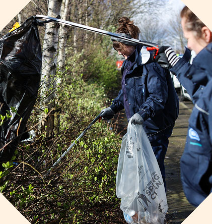 Two volunteer litter pickers picking up rubbish along the roadside.