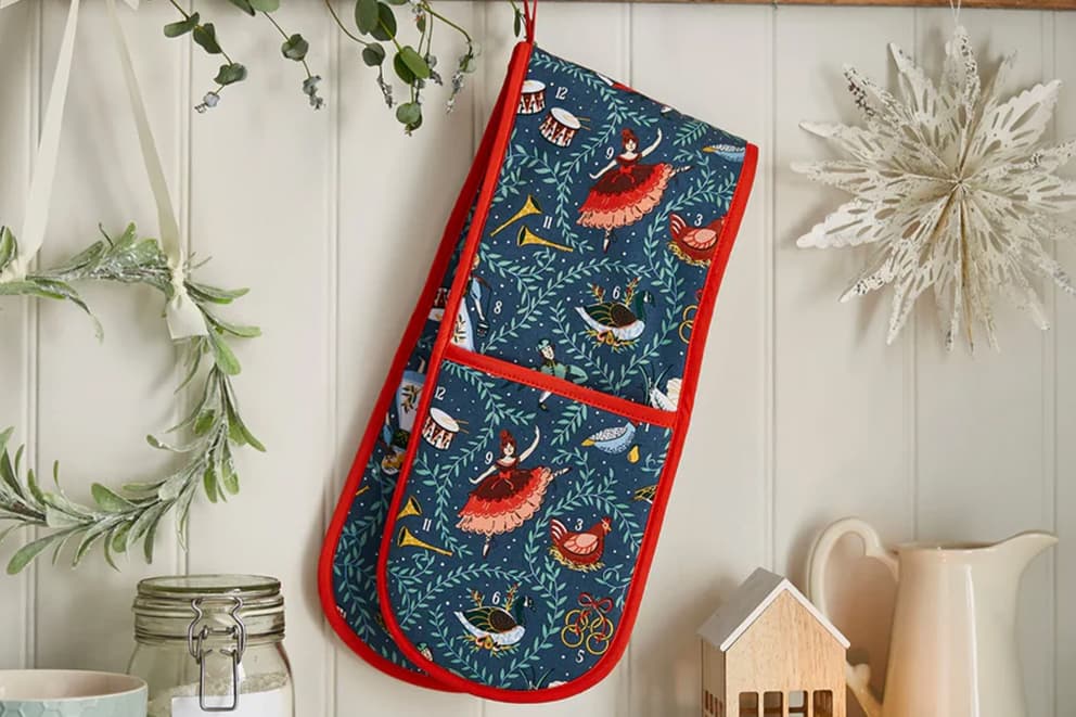 Navy blue oven gloves with red trim and christmas themed prints.