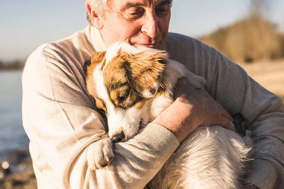 A man lovingly hugging his dog
